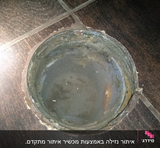 פתח ניקוז עם מים עומדים על רצפה כהה